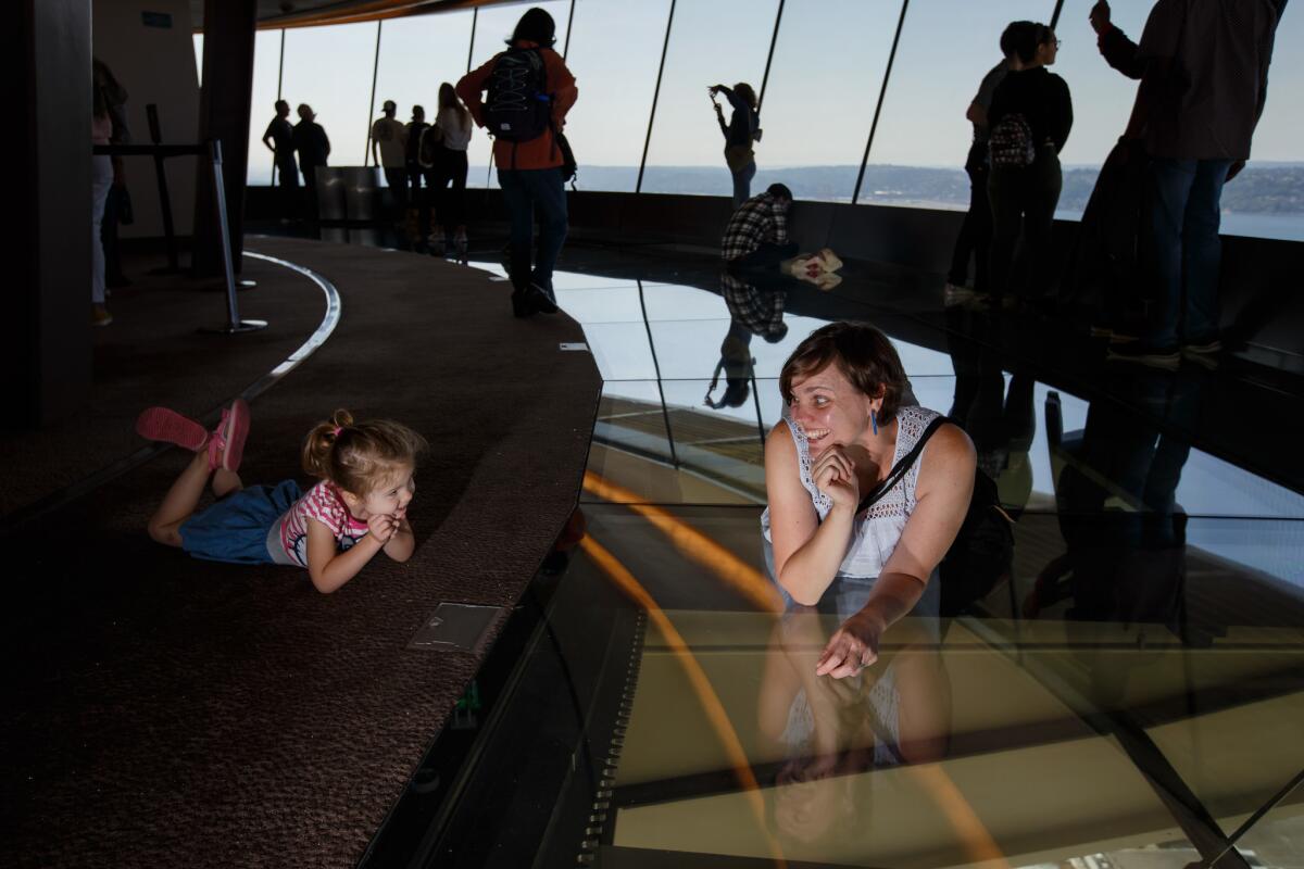 Shauna Bittle lays on the rotating glass floor and tries to convince her daughter Stella Bates, 3, to join her, in the Space Needle, in Seattle, Wash.