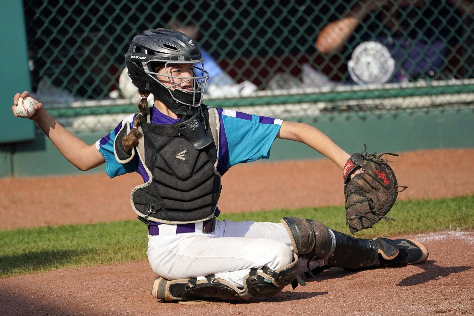 Ella Bruning (8) throws the ball back to the pitcher Myles McCarty as he warms up.