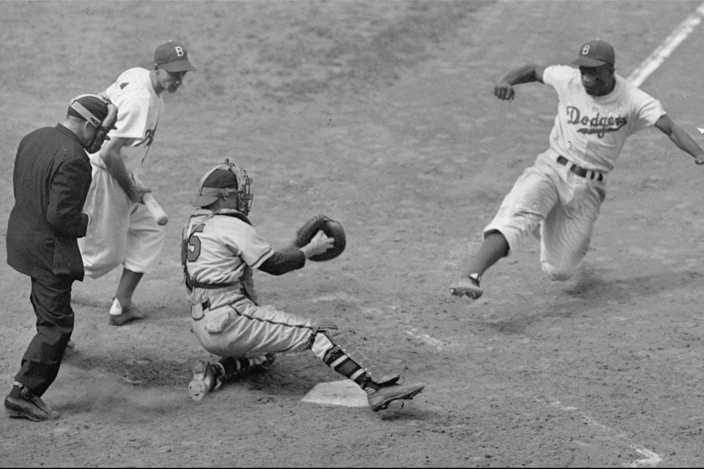 Jackie Robinsonsteals home plate against the Boston Braves at Ebbets Field in 1948.