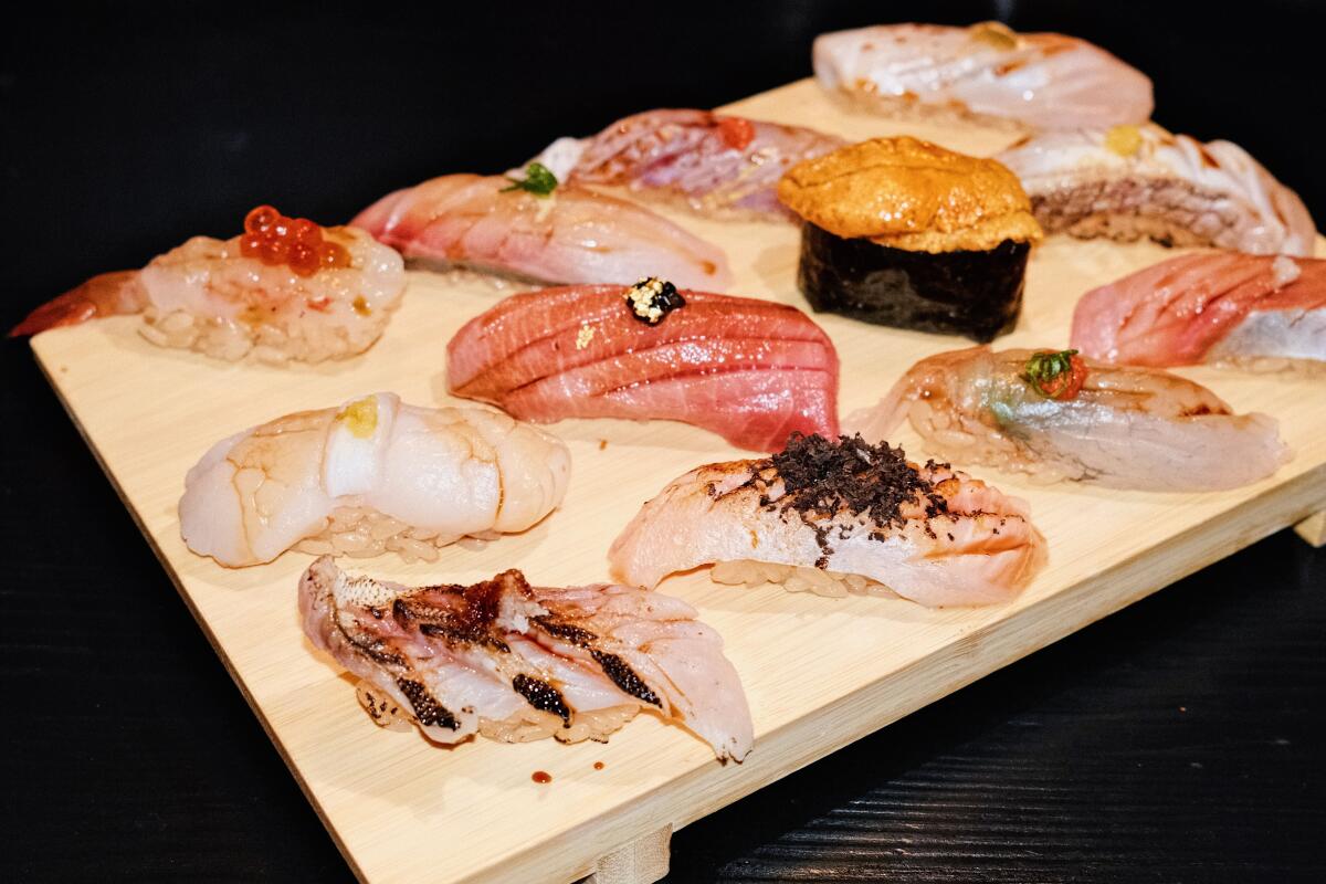 A wooden board holding a 12-piece nigiri omakase, photographed on an angle, at Hato Sushi in Koreatown.
