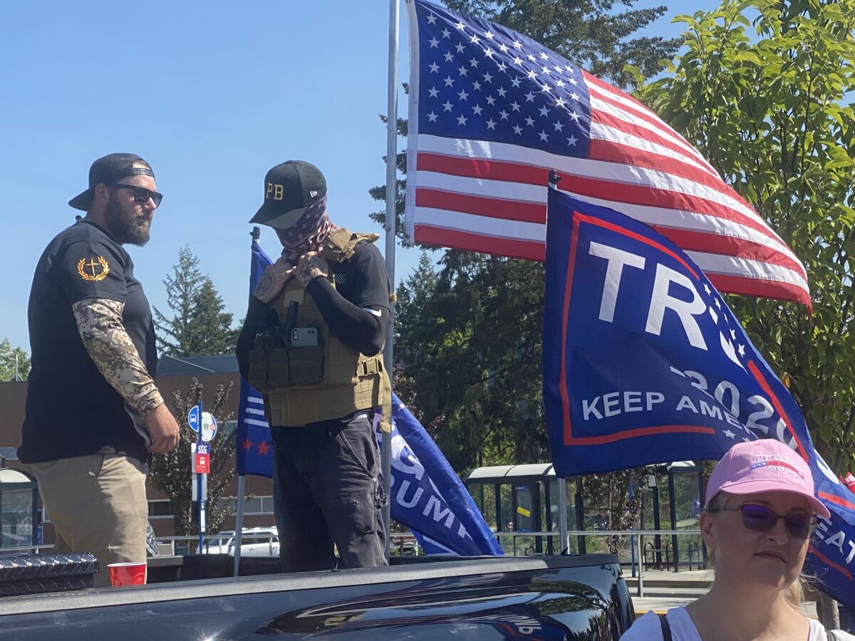 Men wearing symbols of Proud Boys, a violent far-right group, stand watch in Portland, Ore.