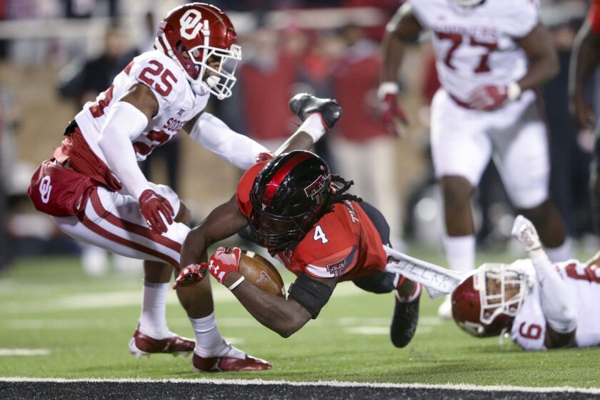 Texas Tech running back SaRodorick Thompson (4) scores a touchdown as Oklahoma defensive backs Justin Broiles (25) and Trey Morrison (6) defend during the second quarter of an NCAA college football game in Lubbock, Texas, Saturday, Nov. 26, 2022. (Ian Maule/Tulsa World via AP)