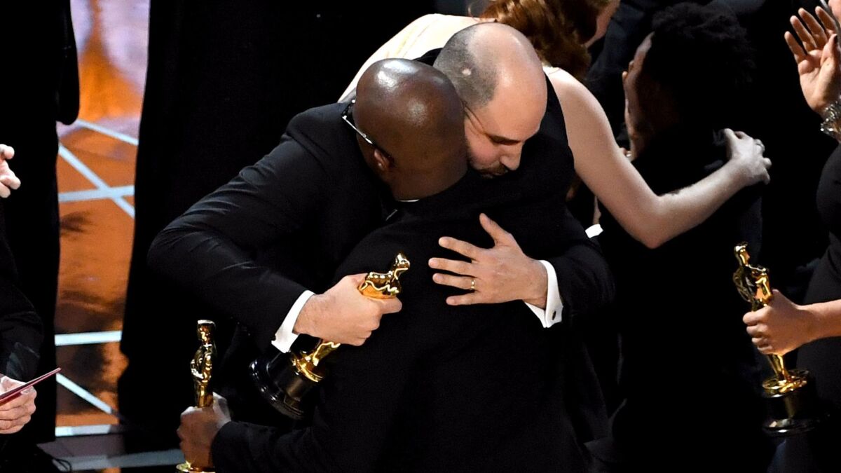 "La La Land" producer Jordan Horowitz embraces "Moonlight" director and writer Barry Jenkins as Horowitz hands over the best picture Oscar onstage at the Academy Awards on Feb. 26 in Hollywood.