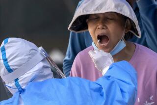 A worker wearing a protective suit swabs a woman's throat for a COVID-19 test on the third consecutive day of mass coronavirus testing in Beijing, Thursday, May 5, 2022. Hong Kong on Thursday reopened beaches and pools in a relaxation of COVID-19 restrictions, while China's capital Beijing began easing quarantine rules for arrivals from overseas. (AP Photo/Mark Schiefelbein)