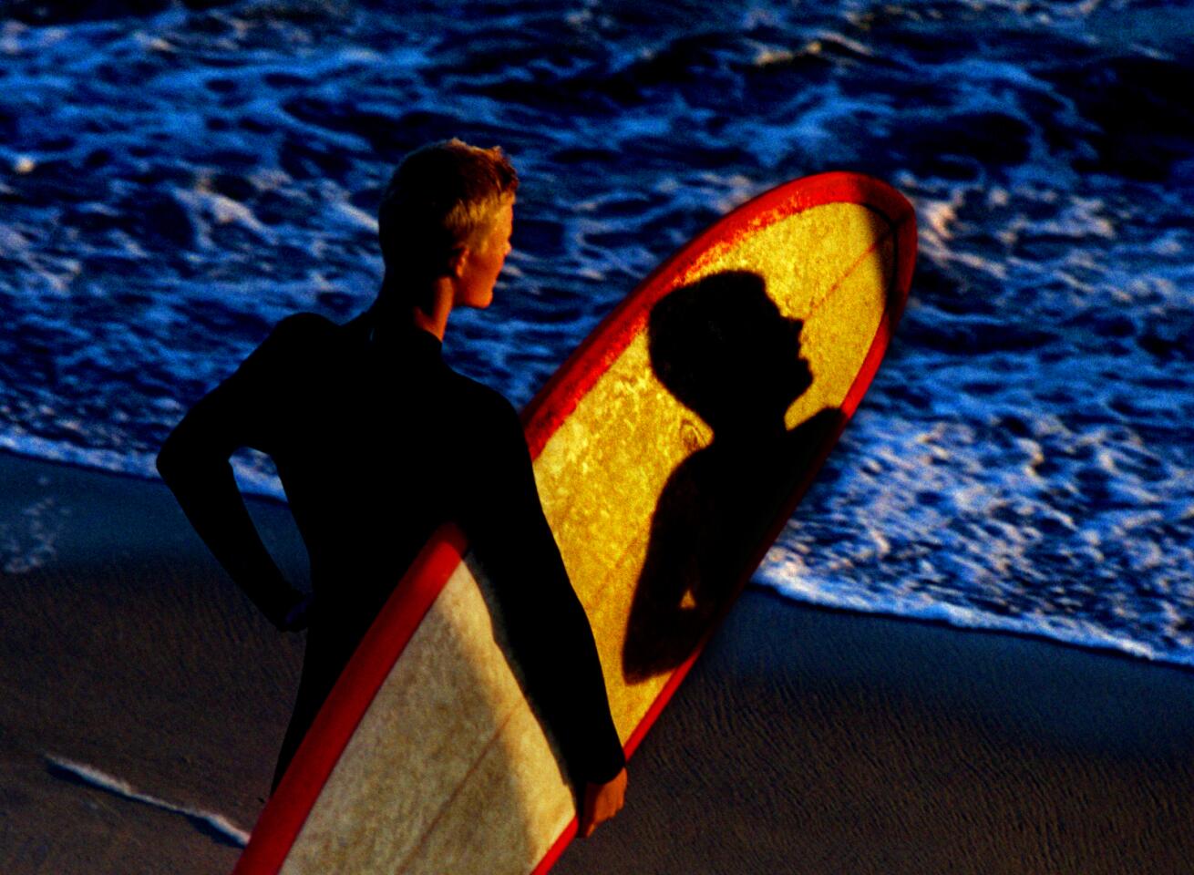 Huntington Beach If you want to learn what waves mean to surfers, go no farther than Huntington Beach, which proudly claims the title Surf City. Here, the water isn't just a recreational pastime -- it's a lifestyle. The day begins and ends with glorious sunlight and endless rides, which is why roughly 11 million visitors come each summer to watch the show. The shadow of a fellow surfer falls across another surfer's long board beneath the Huntington Beach Pier. For more in this series exploring Southern California's beaches, visit our Cruising the Coast page.