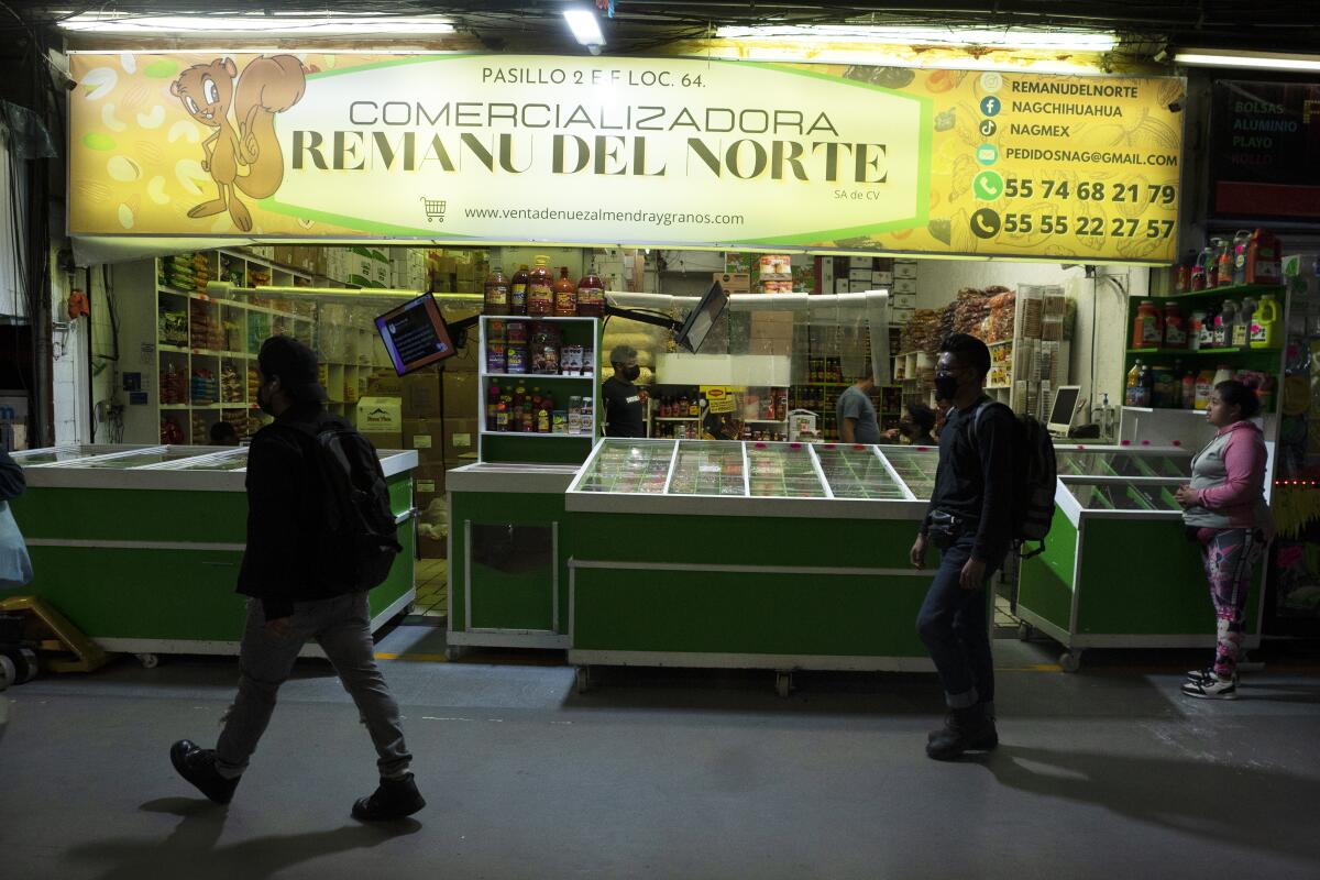 ARCHIVO - La gente pasa frente a una tienda de comestibles donde trabajan inmigrantes haitianos