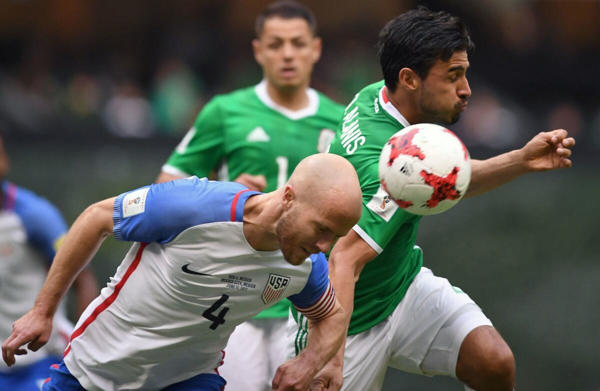 U.S. midfielder Michael Bradley tries to head the ball away from Mexico's Oswaldo Alanis.