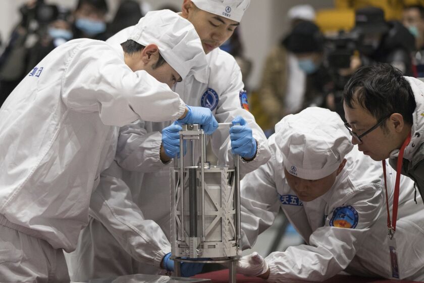 FILE - In this Thursday, Dec. 17, 2020 photo provided by China's Xinhua News Agency, technicians prepare to weigh a container carrying moon samples retrieved by China's Chang'e 5 lunar lander in Beijing. In a report published in the journal Nature Geoscience on Monday, March 27, 0223, scientists announced they have discovered a new and renewable source of water on the moon for future explorers in the lunar samples. Water was embedded in tiny glass beads in the lunar dirt where meteorite impacts occur. (Jin Liwang/Xinhua via AP, File)
