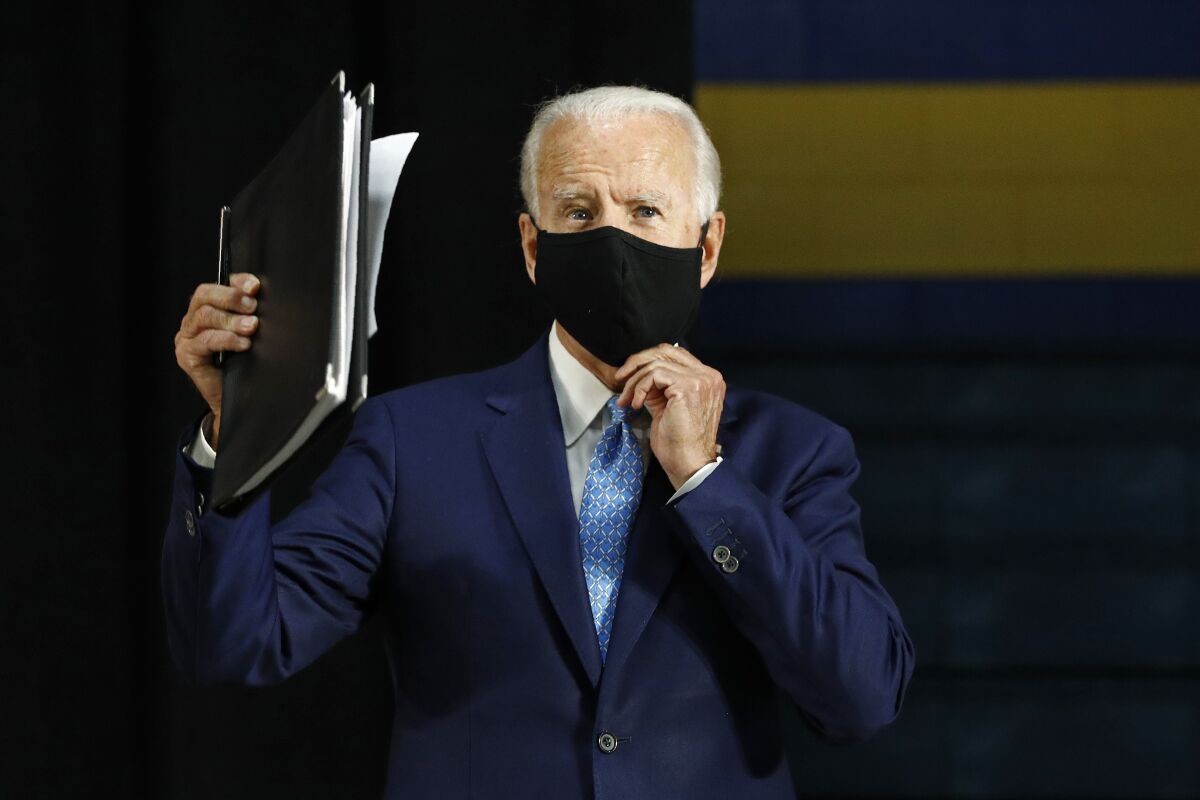 Joe Biden puts on a face mask as he campaigns Tuesday in Wilmington, Del.
