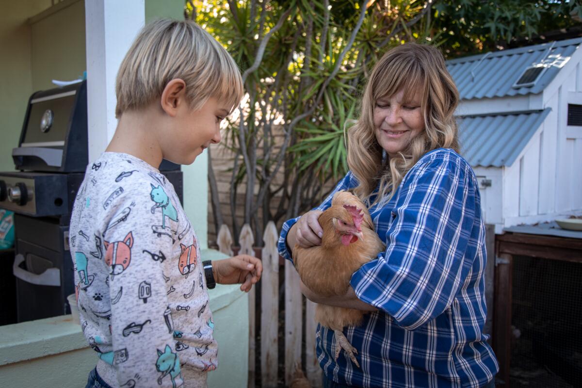 Liam Syren, 8, and his mother, Fredrika, pet one of the five family chickens in their Talmadge neighborhood back yard.