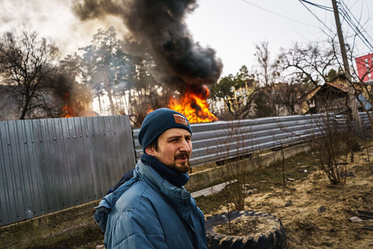 A man stands near a burning home in Irpin, Ukraine.