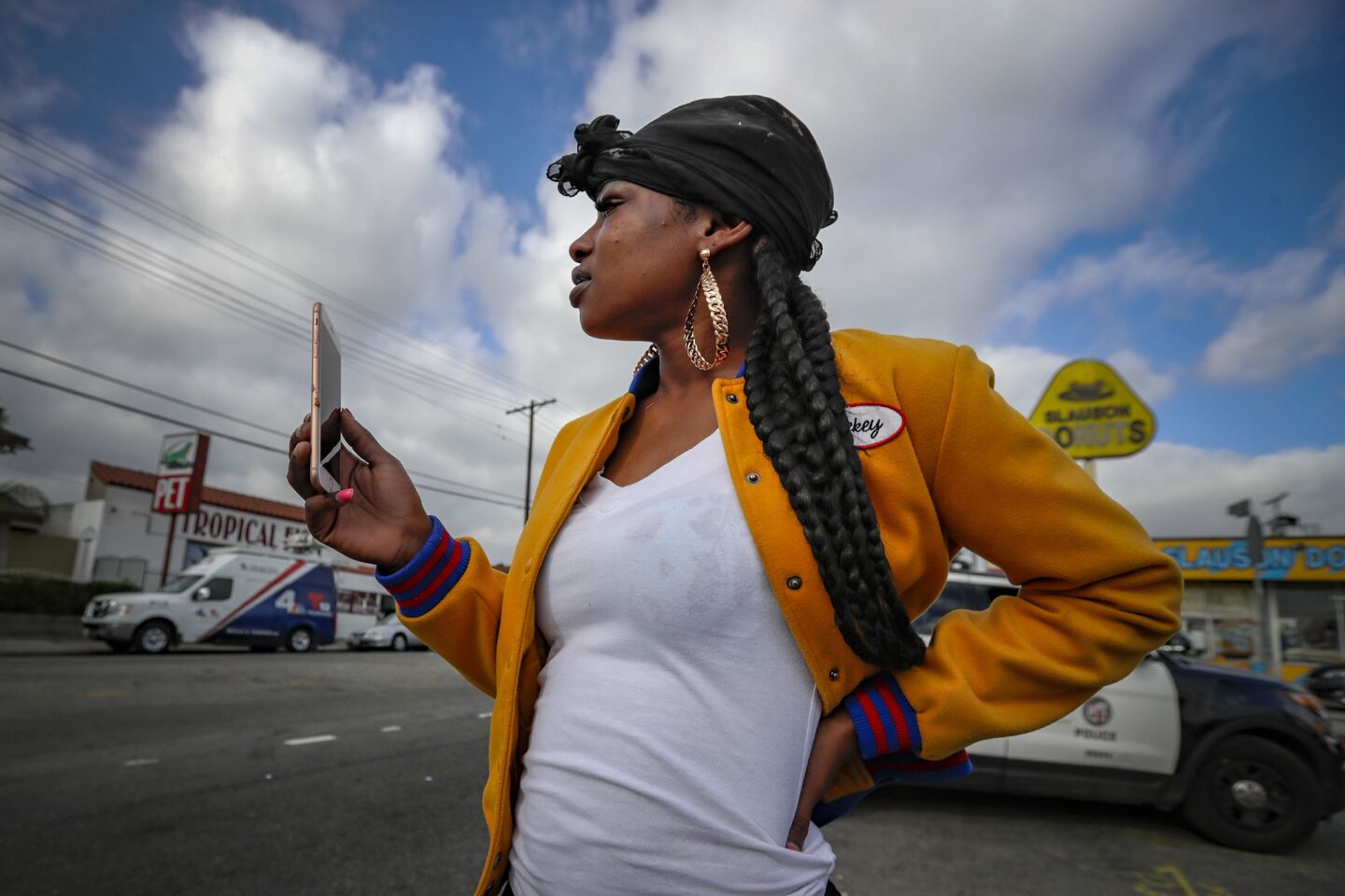 Nene Vauters, 28, stands behind police crime-scene tape to pay her respects at a makeshift memorial for Nipsey Hussle on April 2.
