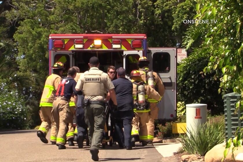 Del Mar crews roll an unresponsive man toward an ambulance Friday afternoon following a house fire on Luneta Drive.