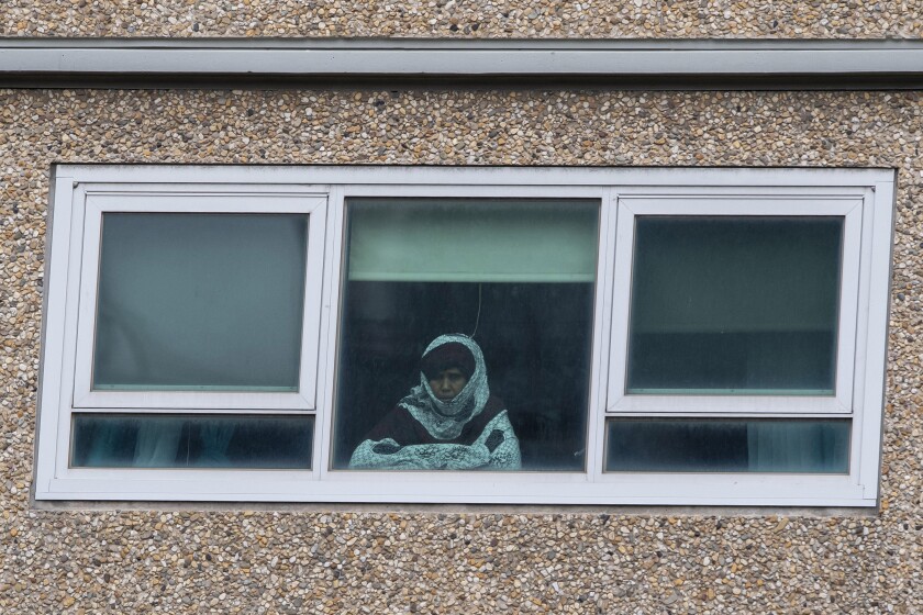A woman peers from a locked-down public housing tower in Melbourne, Australia.