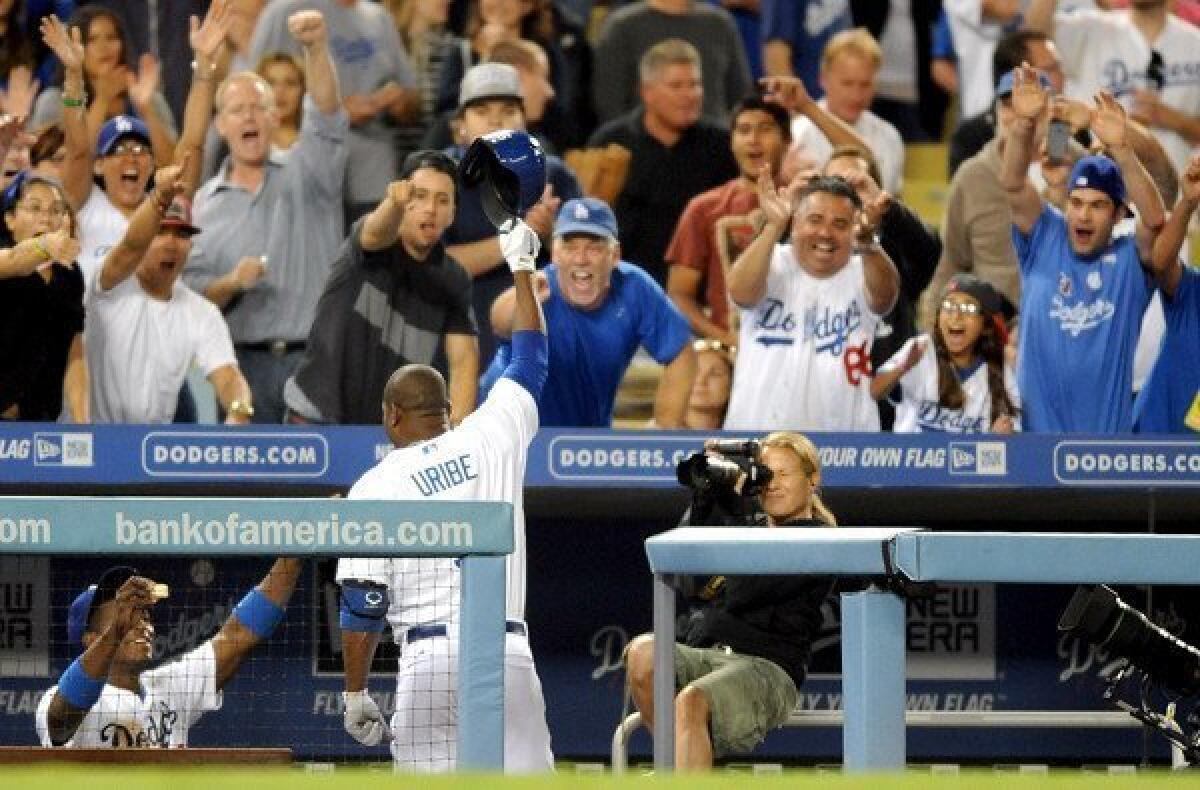 Dodgers third baseman Juan Uribe comes out of the dugout for a standing ovation in the fifth inning after hitting his third solo home run against the Diamondbacks on Monday night at Dodger Stadium.