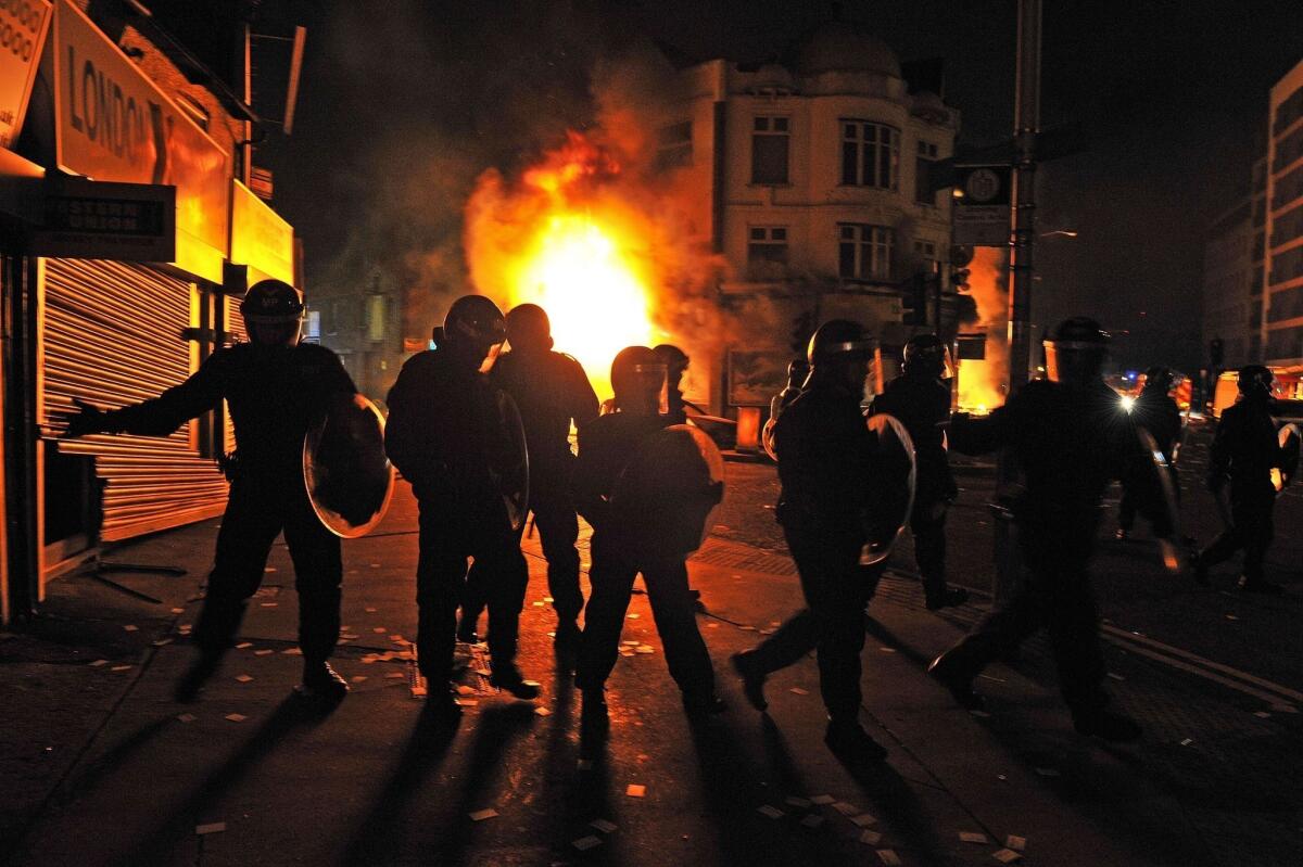 British riot police stand in front of a burning building in Croydon on Aug. 8, 2011, the third night of unrest that followed a fatal police shooting.