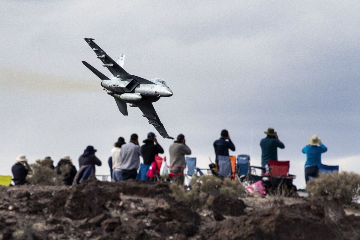 Photographers train their cameras at an F-18 fighter jet from Lemoore Naval Air Station as it dives into Rainbow Canyon.
