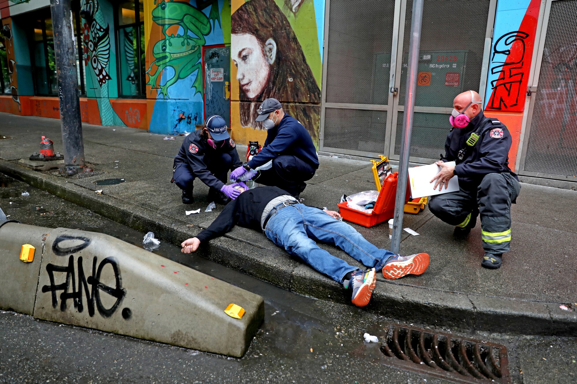 Medics attend to a man lying on a city sidewalk