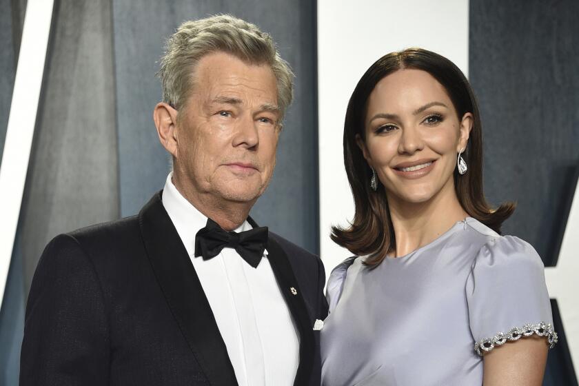 David Foster poses in a black tuxedo with Katharine McPhee smiling in a gray dress.