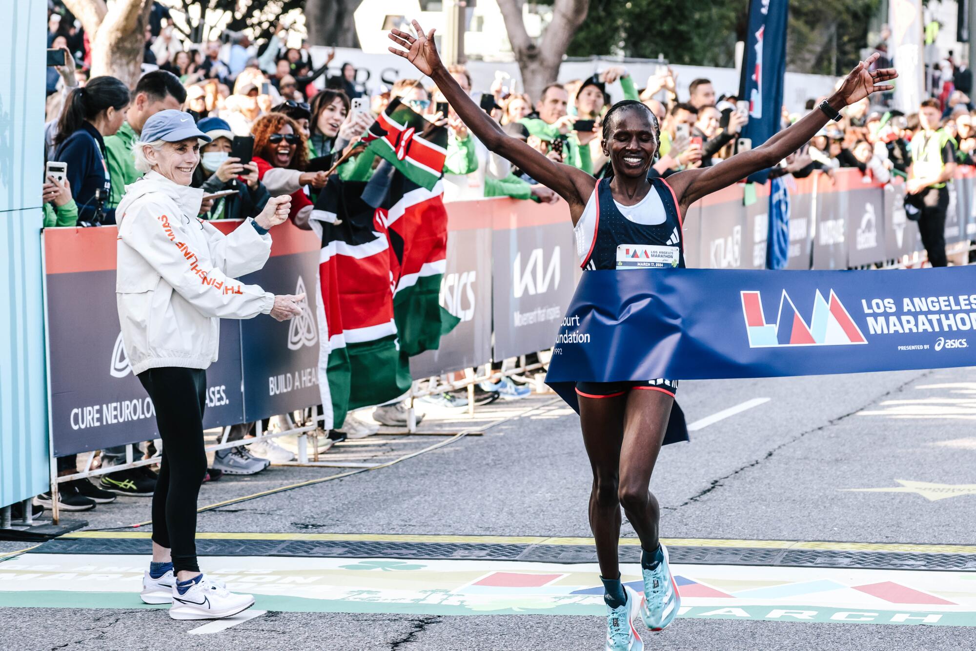 Stacy Ndiwa raises her arms at the L.A. Marathon finish line.