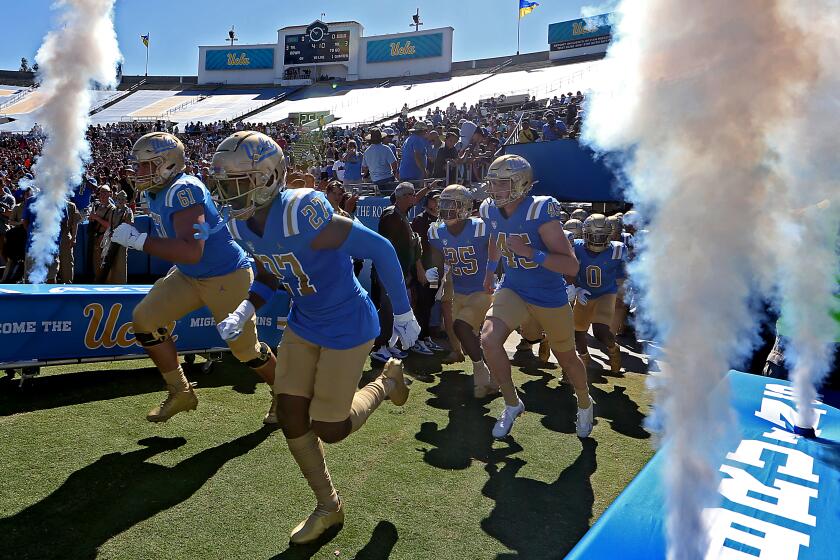 The UCLA football team runs onto the field before facing Washington State on Oct. 7