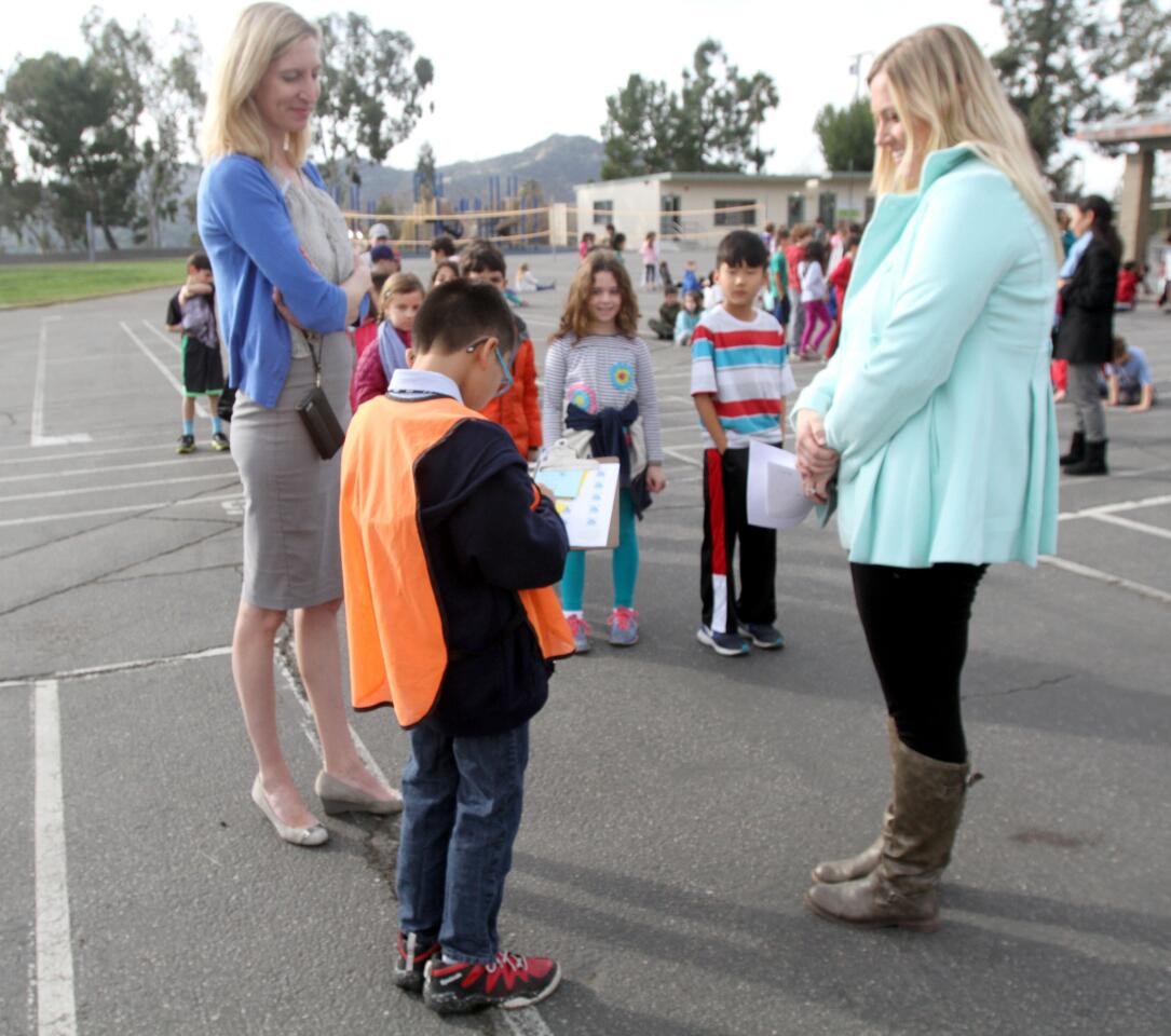 With La Cañada Elementary School Principal Emily Blaney, left, looking on, fifth-grader Michael Kwan, the principal for a day, gives an award to Ms. Carey Durfee and her second-grade class during recess on Tuesday, Jan. 19, 2016.