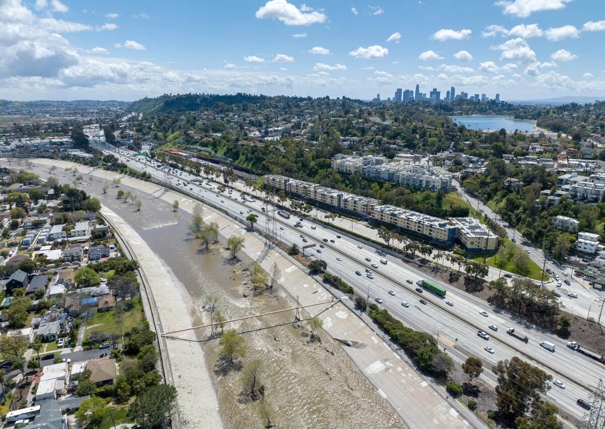An aerial view of the Los Angeles River flows through a concrete channel and near a residential neighborhood.