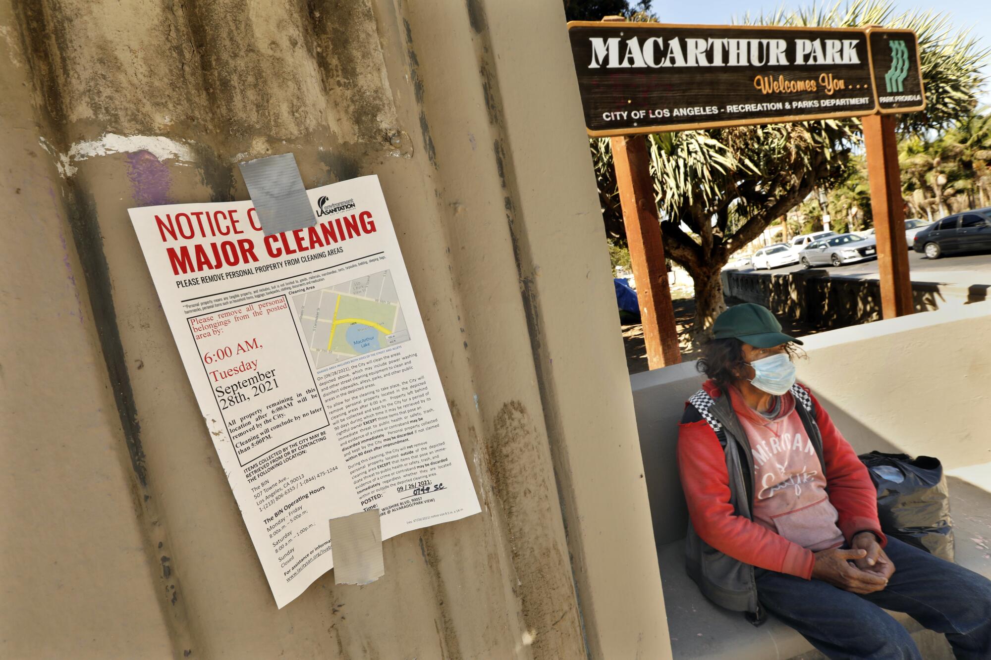 A masked person sits at MacArthur Park