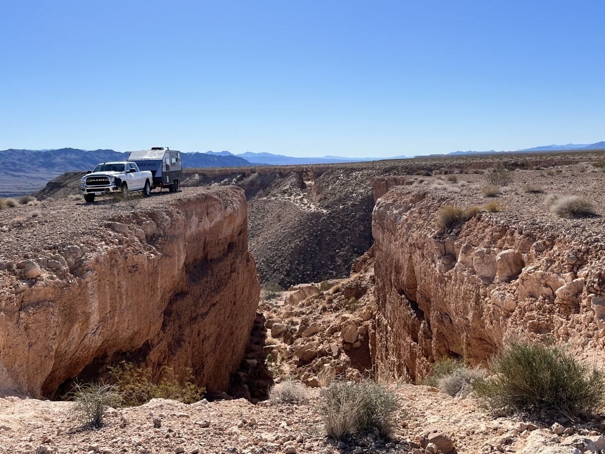 A pickup truck and RV parked alongside a gap in a mesa.
