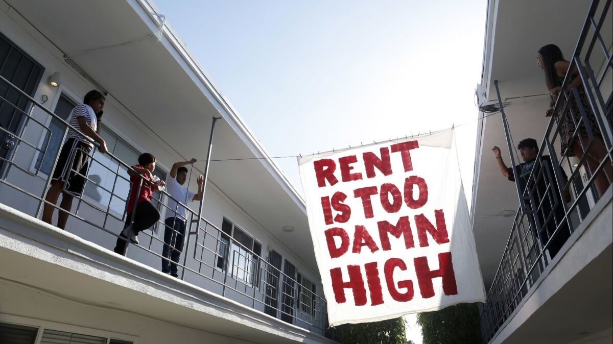 Organizers with Housing Long Beach, a local advocacy group, hang up a sign in the courtyard of an apartment complex on Cedar Avenue in Long Beach.