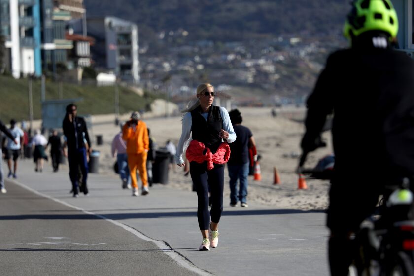 REDONDO BEACH, CA - APRIL 27: People walk along the boardwalk on Tuesday, April 27, 2021 in Redondo Beach, CA. U.S. health officials say fully vaccinated Americans don't need to wear masks outdoors anymore unless they are in a big crowd of strangers (Associated Press). (Gary Coronado / Los Angeles Times)