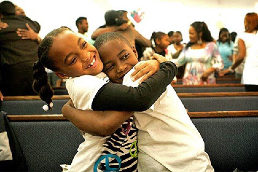 Children embrace at a Compton church event in January. Faith Inspirational Missionary Baptist Church offers free movies in local parks, and draws large crowds as people feel safer going out.