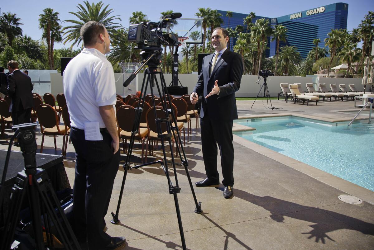 Pac-12 commissioner Larry Scott, right, answers questions during a TV interview in Las Vegas