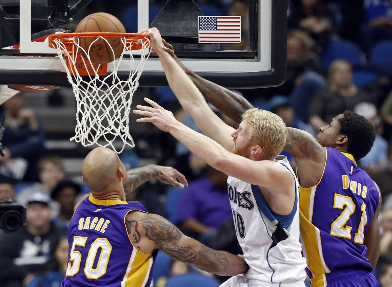 Timberwolves forward Chase Budinger dunks between Lakers defenders Ed Davis (21) and Robert Sacre (50) during the second half of the Lakers' 101-99 overtime victory.