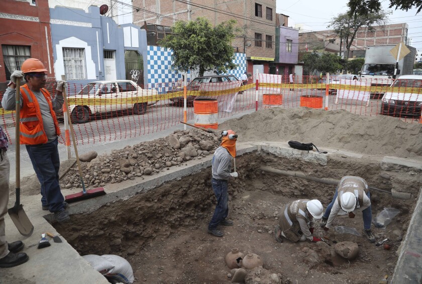 FILE - Archaeologists excavate ancient bones and vessels from a previous Inca culture that were discovered by city workers digging a natural gas line in the Brena neighborhood of Lima, Peru, Feb. 11, 2020. About 300 archaeological finds, some 2,000 years old, have been reported over the past decade during the building of thousands of kilometers (miles) of natural gas pipelines in the capital. (AP Photo/Martin Mejia, File)