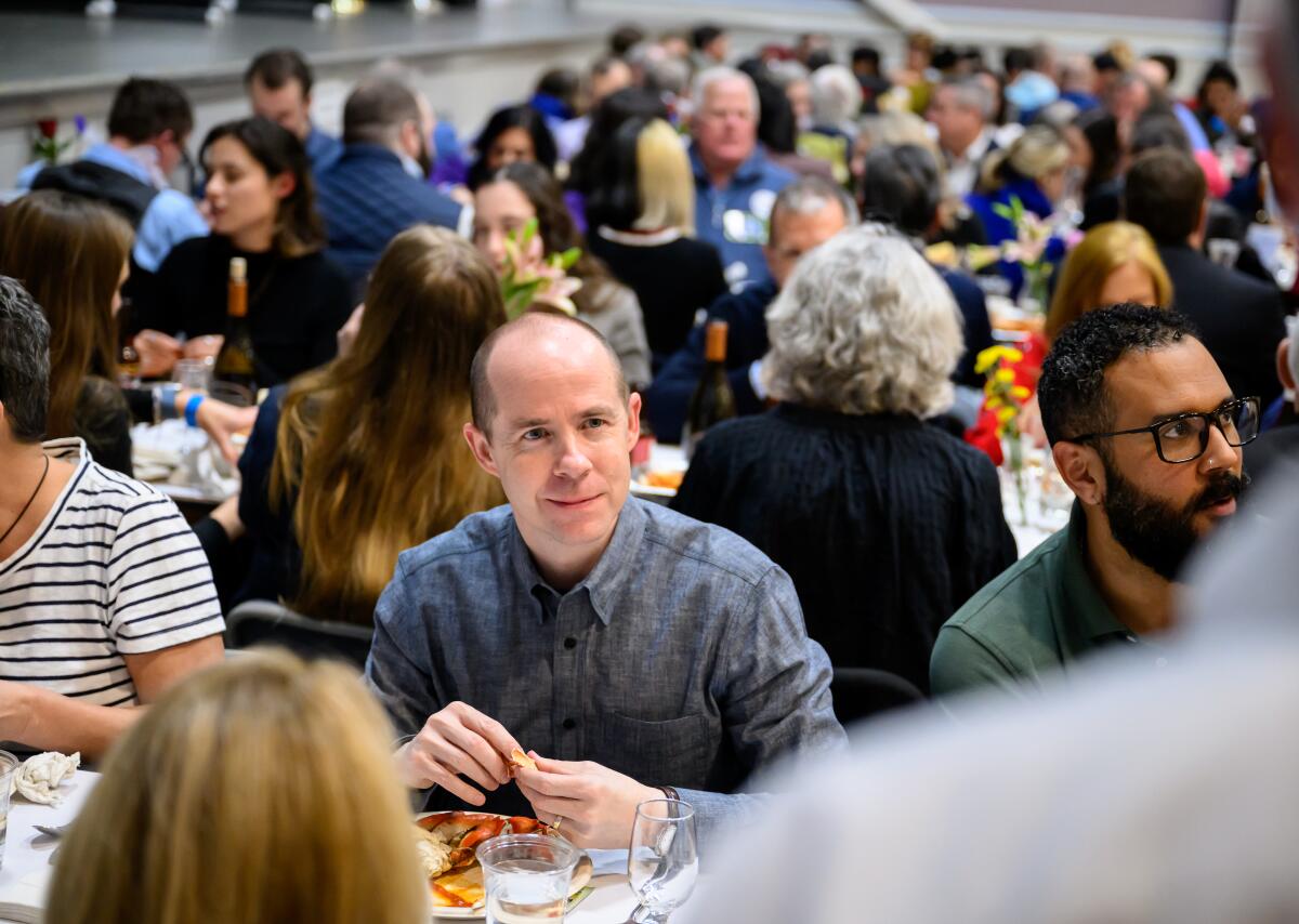 A man sits at a crowded event. 