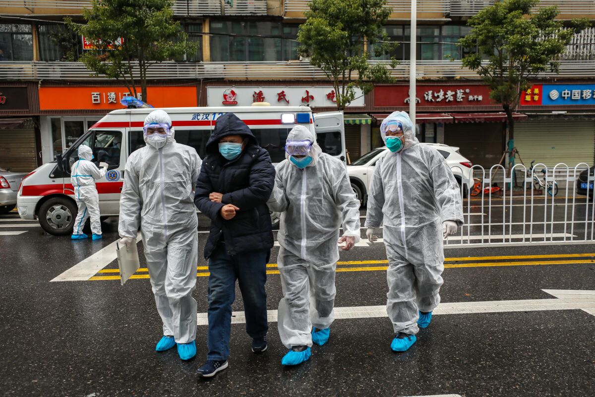 Medical staffers help a patient walk into the hospital in Wuhan. 