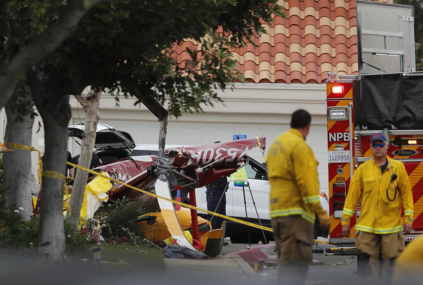 Fire crews work the scene of a helicopter crash that killed three people and injured two others on Shearwater Place in the Bayview Terrace community in Newport Beach.