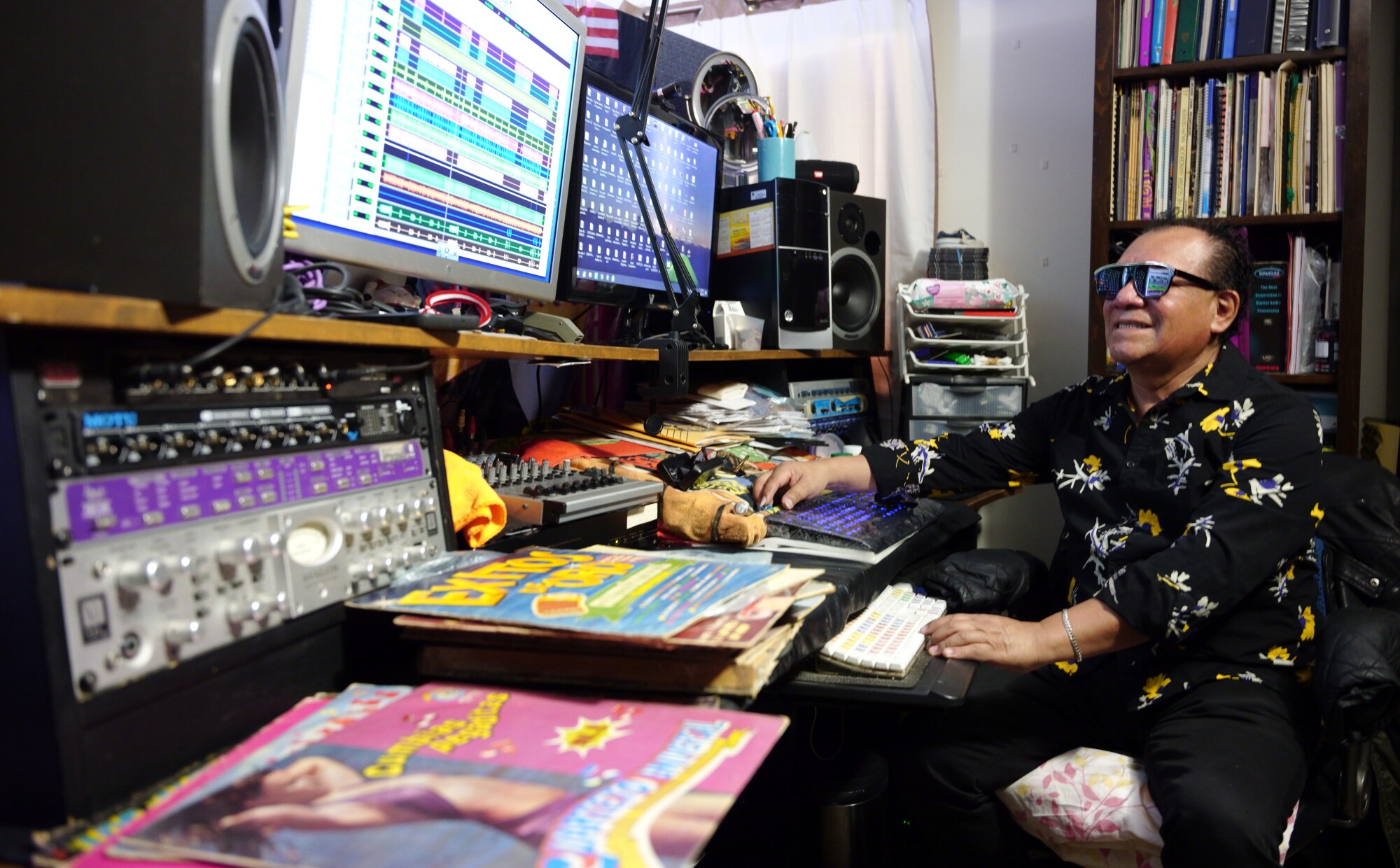 El músico en su estudio casero, rodeado de discos de vinilo originales de cumbia peruana.