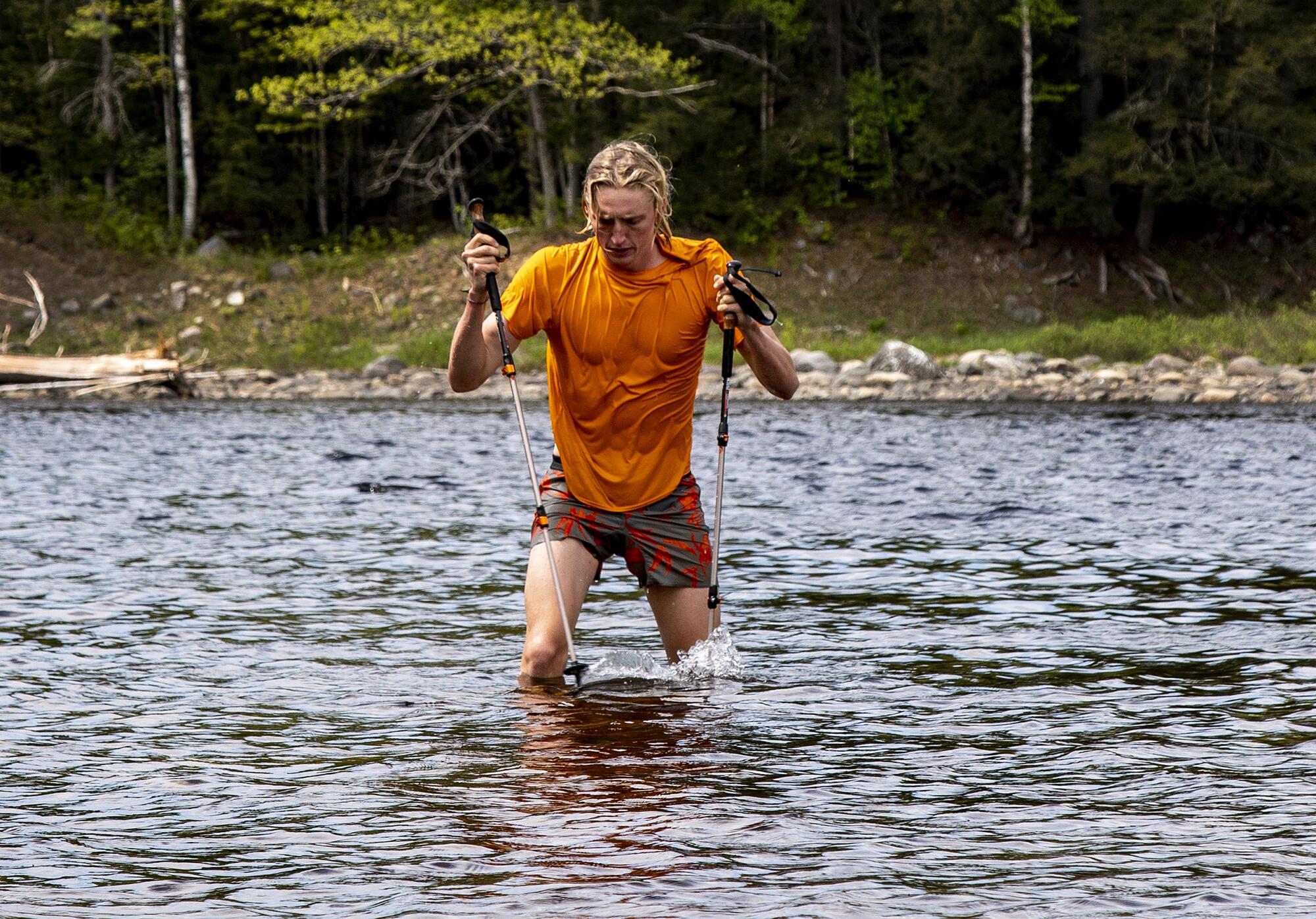 Jackson Parell wades through the Kennebec River with hiking poles
