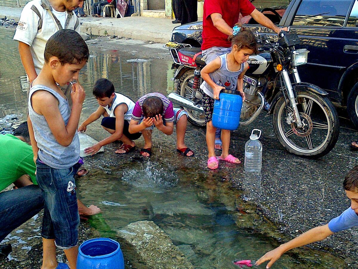 Children wash in and collect water from a pool in an Aleppo neighborhood where the water had been cut off.