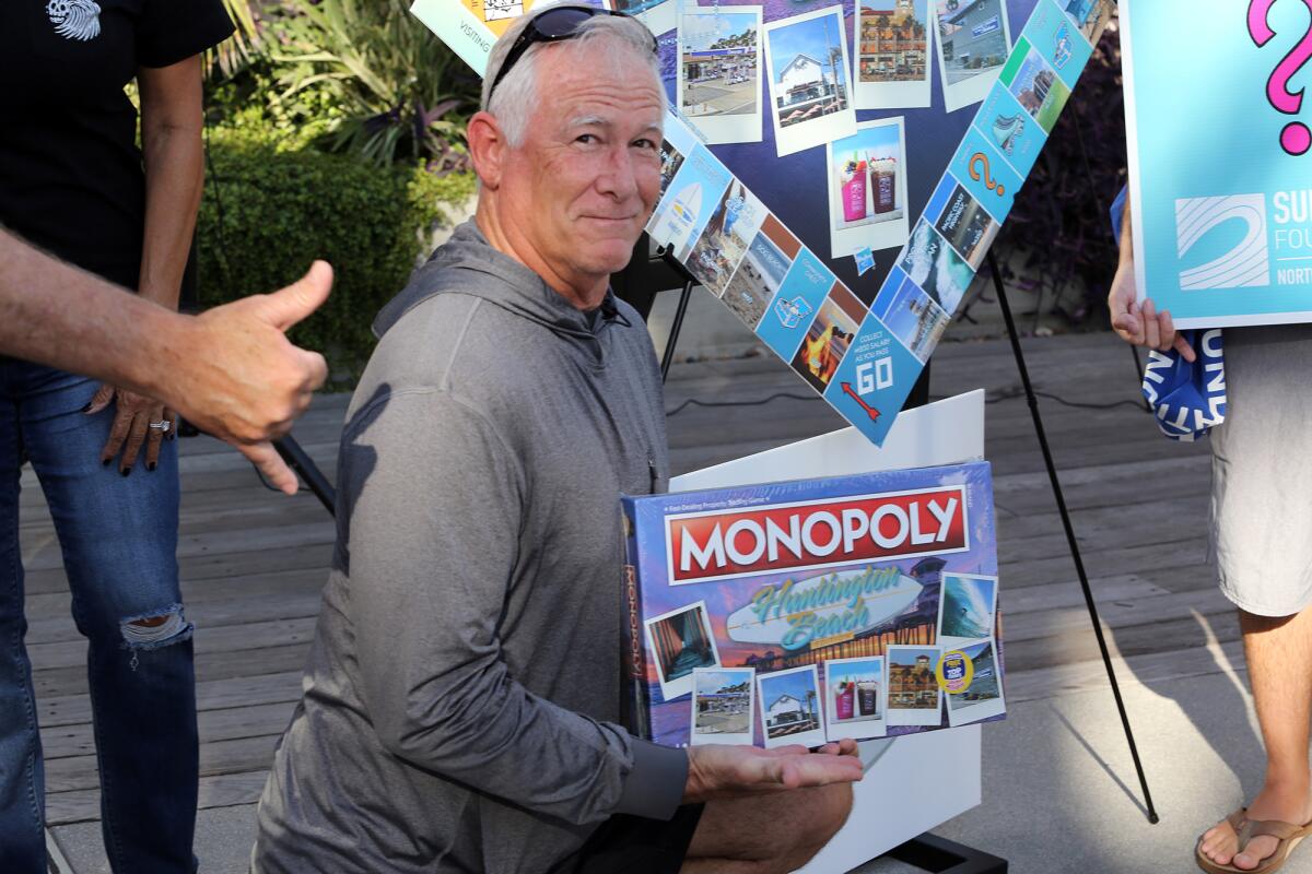 KC Fockler from the Surfrider Foundation poses with the "Monopoly: Huntington Beach edition" game.