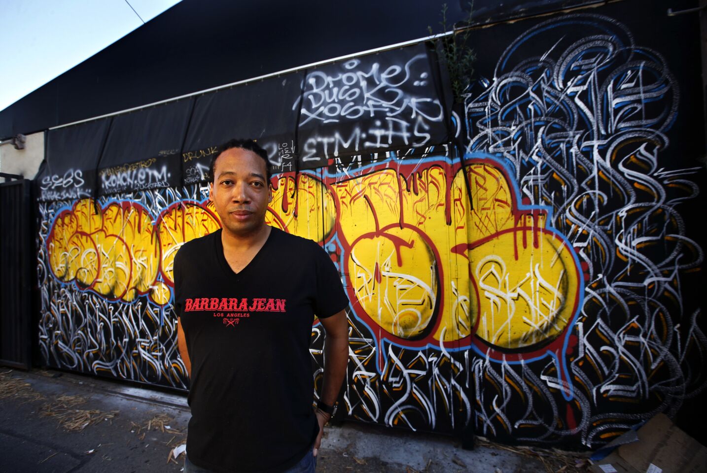 Chef Jason Fullilove stands just outside the walled patio dining area of his restaurant Barbara Jean. The graffiti wall, facing the alley, is made to look on its other side like a quilt.
