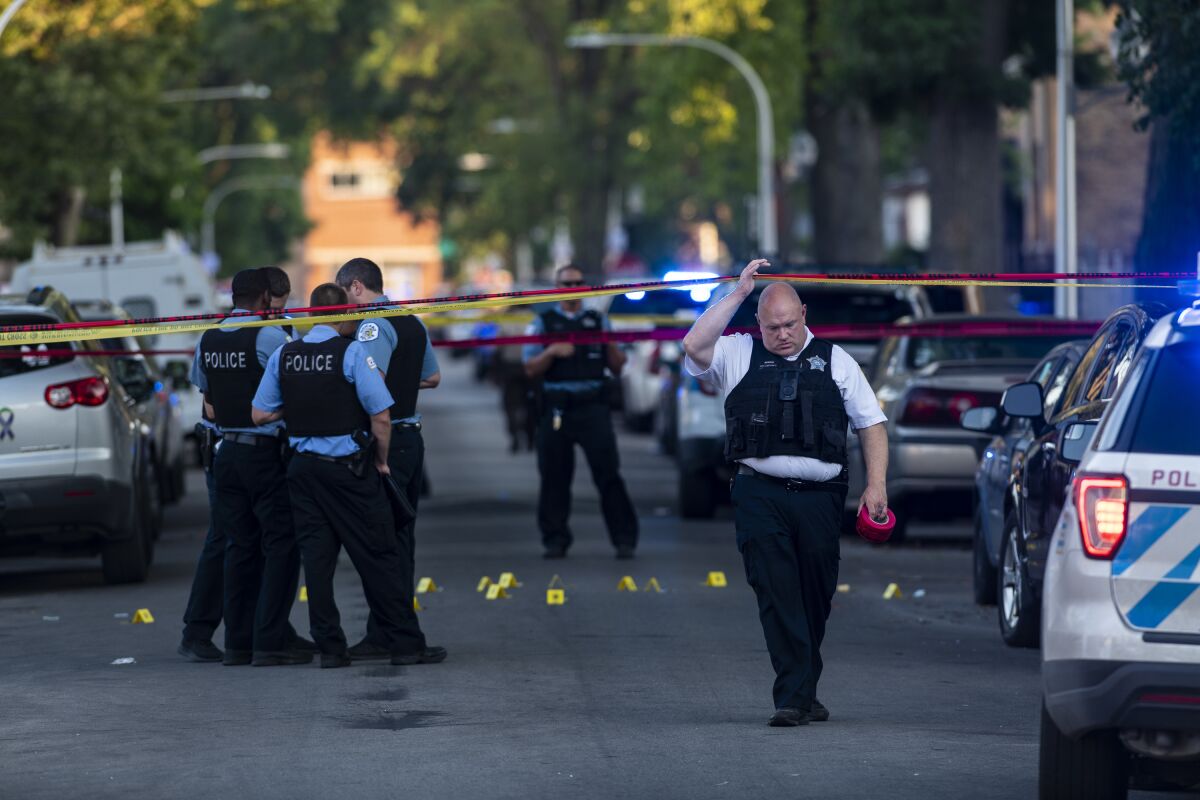 Chicago police officers investigate the scene of a deadly shooting in Chicago on Sunday, July 5, 2020, where a 7-year-old girl and a man were fatally shot during a Fourth of July party Saturday. At least a dozen people were killed in Chicago over the Fourth of July weekend, police said. Scores of people were shot and wounded. (Tyler LaRiviere/Chicago Sun-Times via AP)