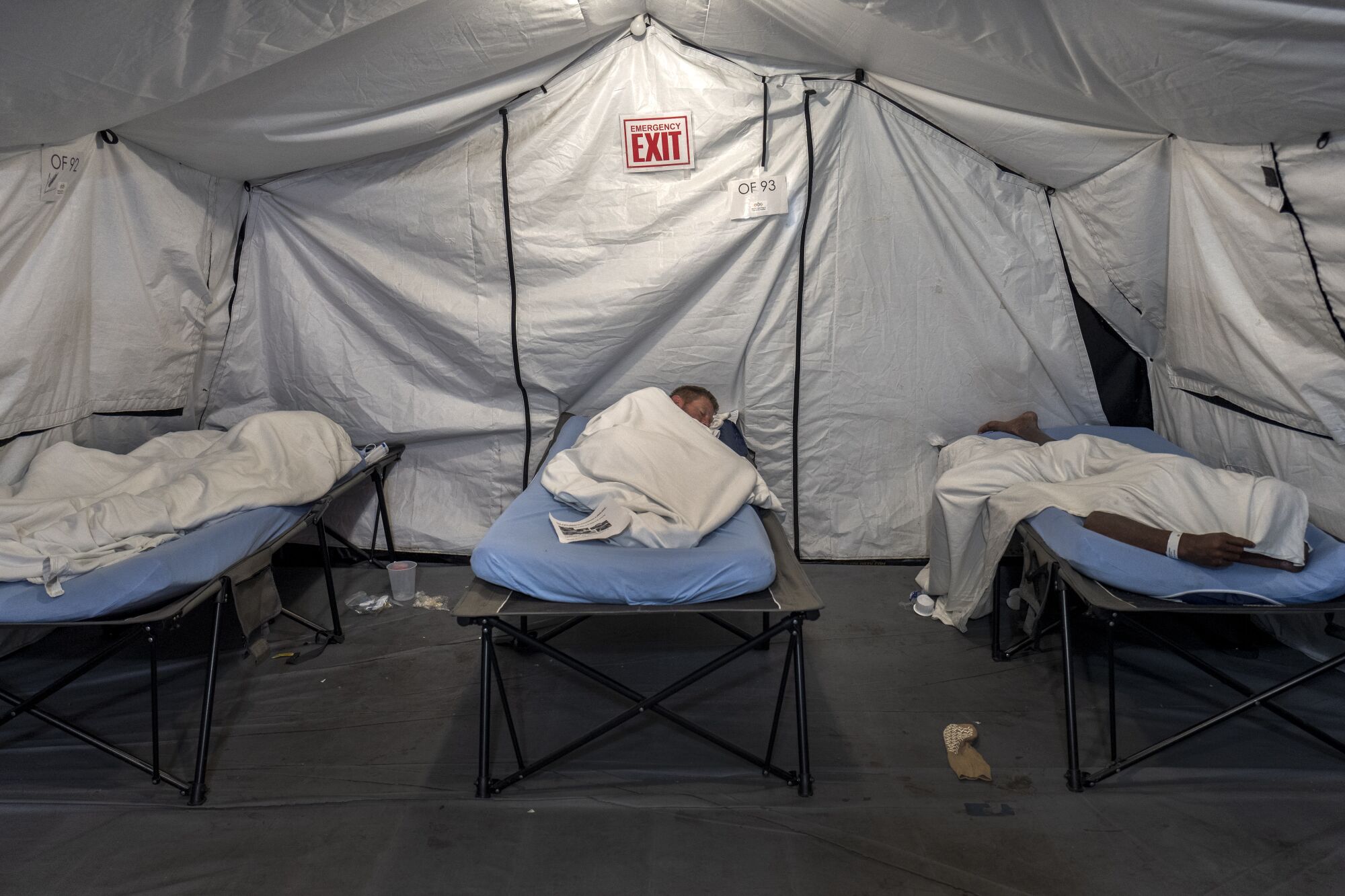 Patients sleep on cots in a tent.