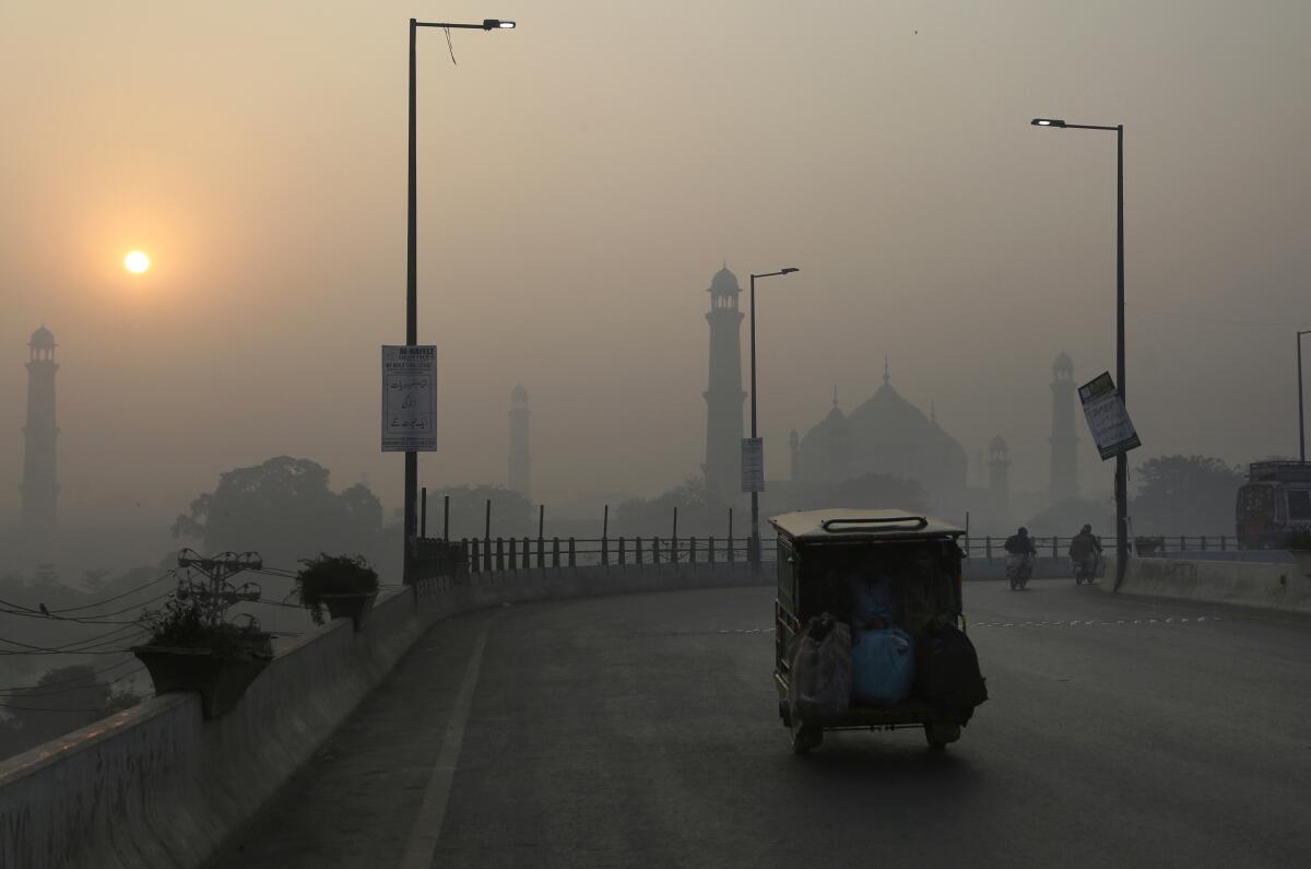 An auto rickshaw on a road as smog surrounds Lahore, Pakistan.