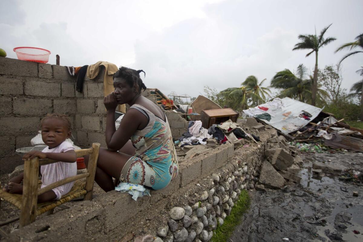 Victor Farah and her daughter sit in the ruins of their home, destroyed by Hurricane Matthew, in Les Cayes, Haiti, on Thursday.