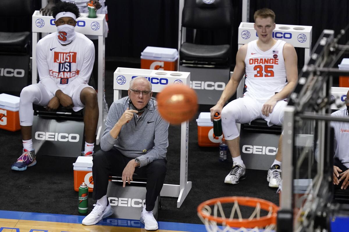 Syracuse head coach Jim Boeheim, seated front, watches a shot as his son guard Buddy Boeheim (35) looks on during the second half of an NCAA college basketball game in the second round of the Atlantic Coast Conference tournament in Greensboro, N.C., Wednesday, March 10, 2021. Syracuse defeated North Carolina State 89-68. (AP Photo/Gerry Broome)