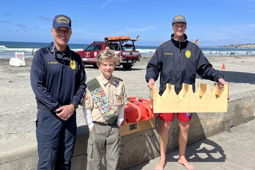 Eagle Scout Emilio De Soto and lifeguards Lonnie Stephens and Benjamin Vander Ploeg show Emilio's custom buoy holder.