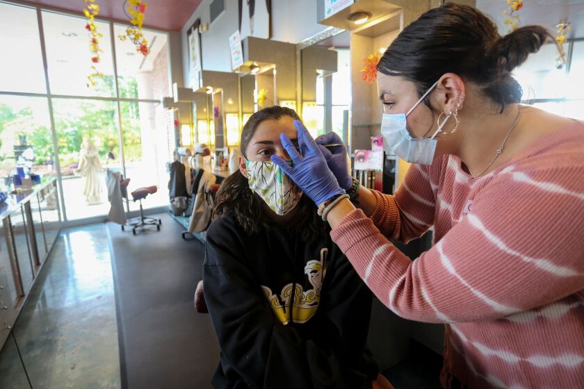 A customer gets her eyebrows waxed at Three-13 Salon, Spa & Boutique on Friday, April 24, 2020, in Marietta, Georgia. The salon had been closed for more than a month due to the new coronavirus. Barber shops, nail salons, gyms and a few other businesses reopened in Georgia on Friday as the Republican governor eased a month-long shutdown despite warnings from health experts of a potential new surge of coronavirus infections. (AP Photo/Ron Harris)